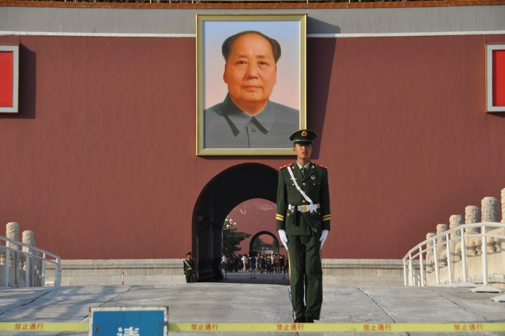 The portrait of Chairman Mao above the central arch of the Gate of Heavenly Peace, with a guard standing at attention below.