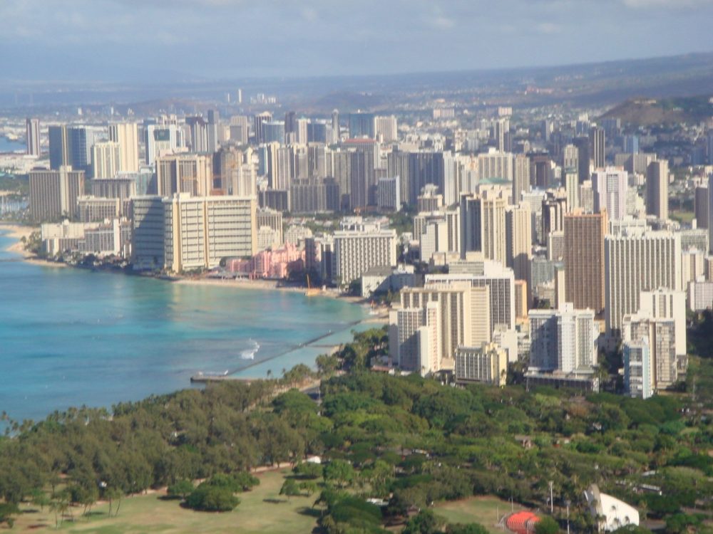 Waikīkī and its hotels seen from Diamond Head (Lēʻahi), with the reef, the shoreline and parkland below.