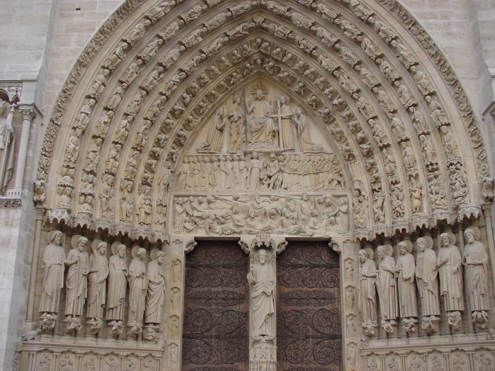 The carved central doorway of Notre-Dame, with rows of statues on either side of the doors.