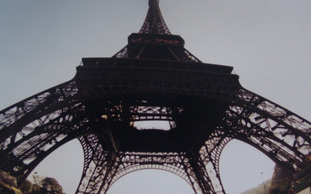Looking straight up at the iron lattice of the Eiffel Tower from beneath it.