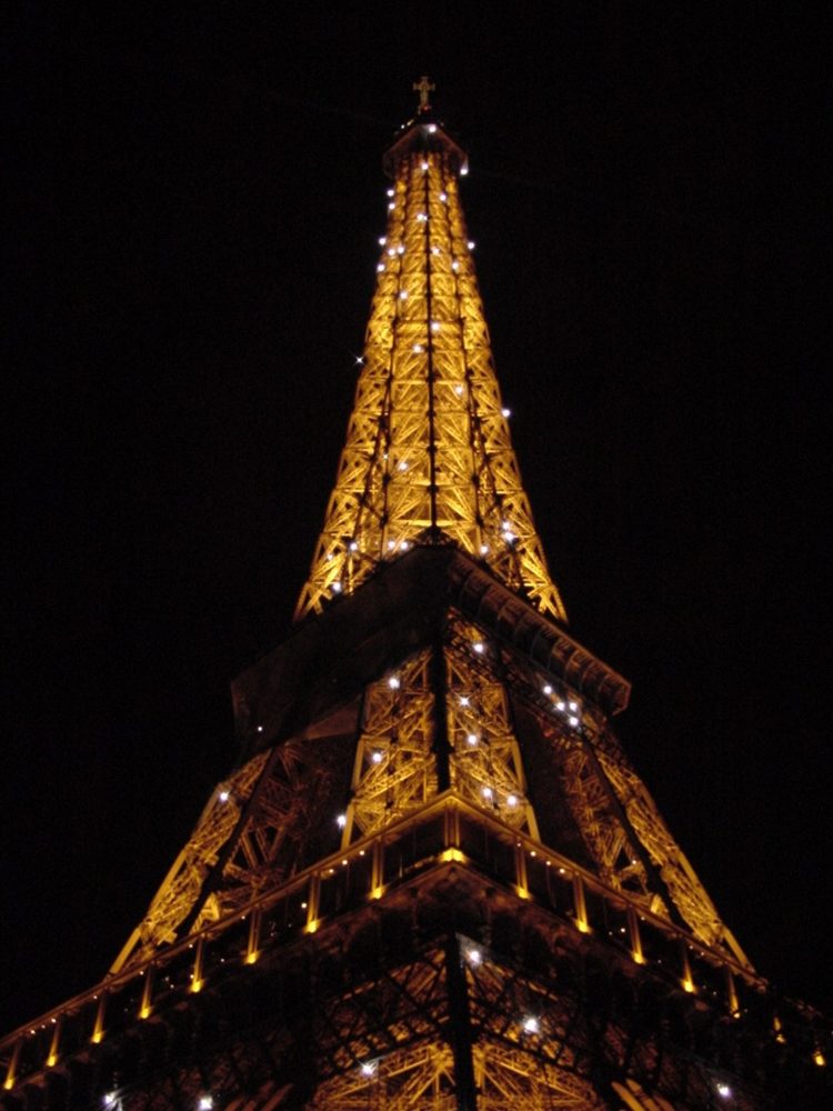 The Eiffel Tower lit up in gold at night.