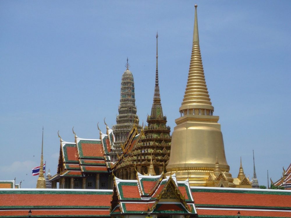 The golden chedi and spires of Wat Phra Kaew rising above the tiled roofs of the Grand Palace, Bangkok.