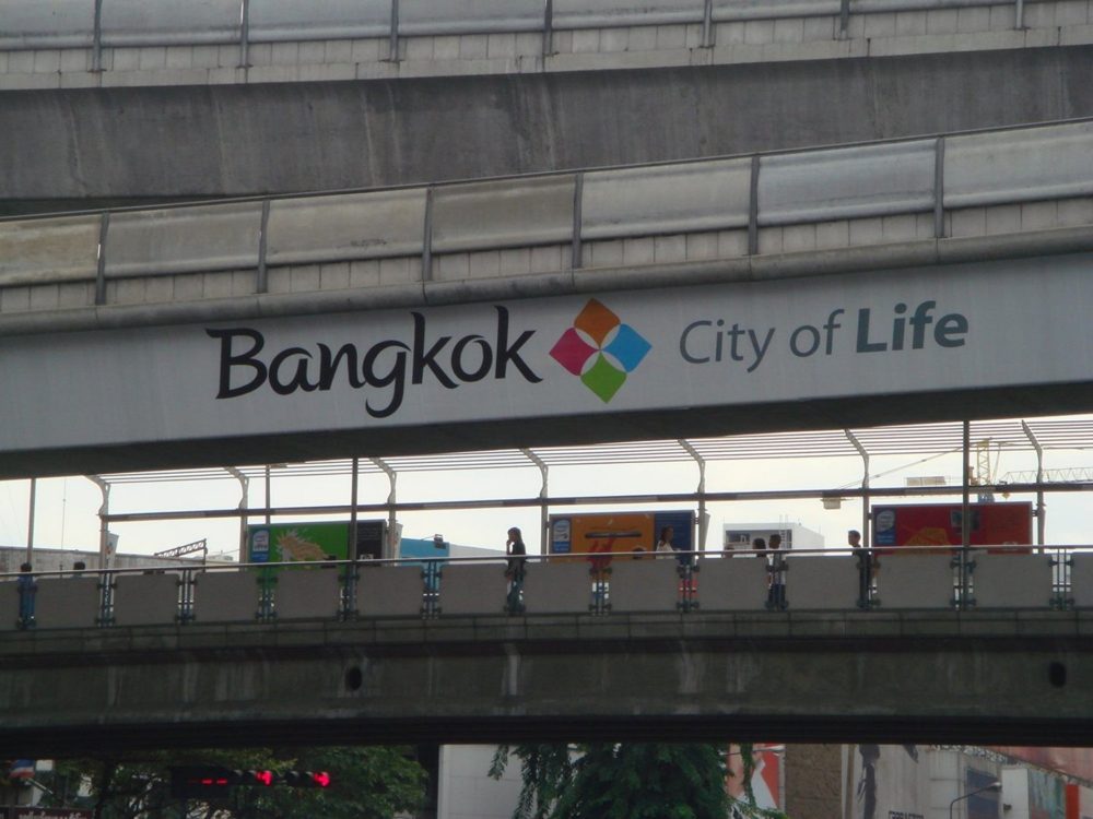 A “Bangkok City of Life” banner on an elevated walkway beneath the Skytrain line.